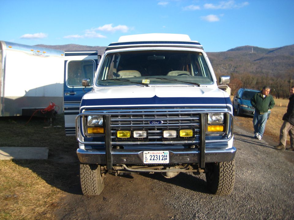 1988 Ford E350 van front view with push bumper, auxiliary lights, and Virginia license plate 22312. Another van and a blue car are visible