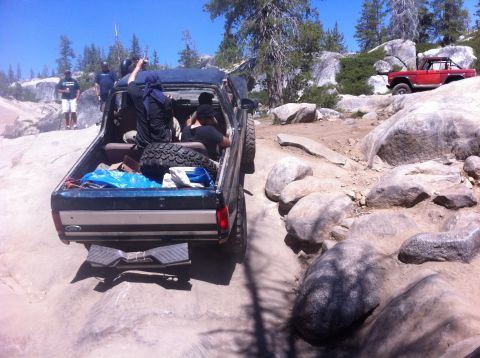 1990 Ford Bronco - Off-roading adventure with friends on a sunny day, navigating challenging rocky terrain.