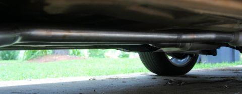 1976 Ford Ranchero - The exhaust system of a vehicle is shown from below, with a tire in the background.