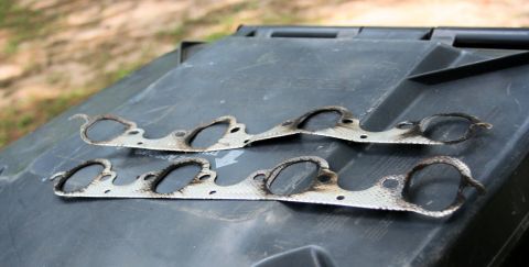 1976 Ford Ranchero - Two used exhaust manifold gaskets are shown resting on a dark surface, with the SuperMotors logo in the corner.