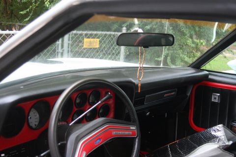 1976 Ford Ranchero - The interior of a 1976 Ford Ranchero features red trim accents on the dashboard and door panels.