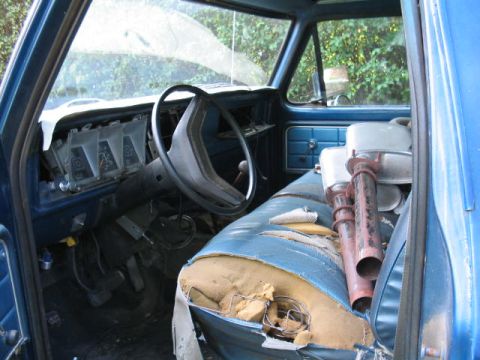 1979 Ford Bronco - Interior view of a 1979 Ford Bronco, a dashboard, steering wheel, and exhaust pipes on the seat.