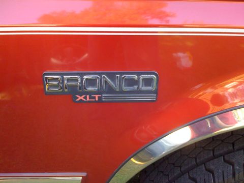 1996 Ford Bronco - Close-up of the Bronco XLT emblem on a red 1996 Ford Bronco.