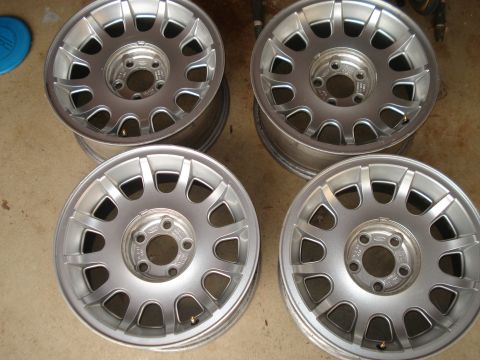 2000 Ford Crown Victoria - Four silver alloy wheels are shown, each with a 15-spoke design and a central Ford logo.