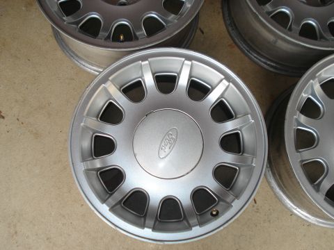 2000 Ford Crown Victoria - Set of four silver Ford wheels, likely from a 2000 model year vehicle.