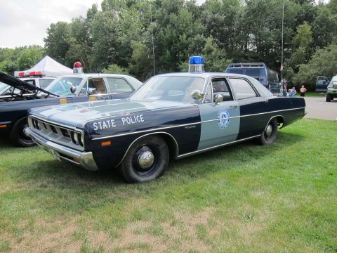 1991 Ford LTD Crown Victoria - two-tone blue Plymouth marked STATE POLICE with a round seal and roof light bar parked on grass among other cruisers.