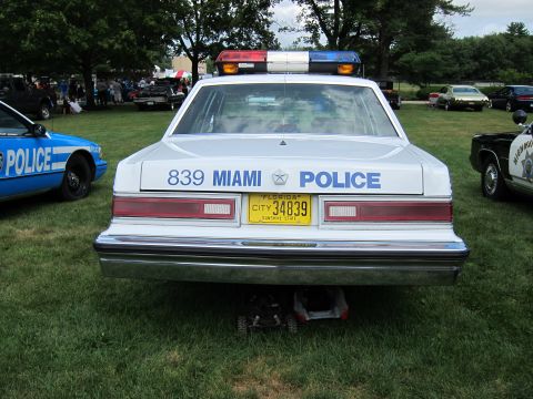 1991 Ford LTD Crown Victoria - Rear view of white Miami Police sedan number 839 with light bar and yellow Florida plate, parked on grass at a car show.