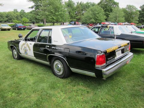 1991 Ford LTD Crown Victoria - Black-and-white Ford Highway Patrol sedan marked Safety and Service, rear three-quarter view on a grassy show field.