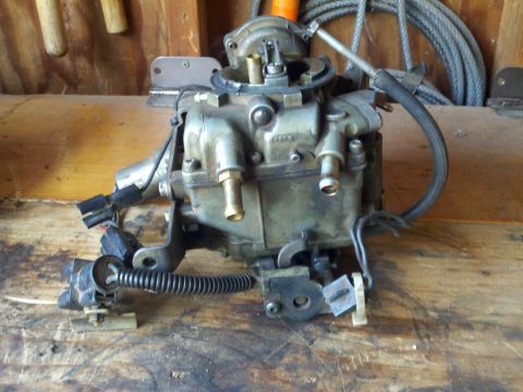 1986 Ford Bronco - A close-up view of a carburetor, a crucial component for internal combustion engines, showing its intricate mechanical and electrical conne…