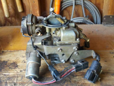 1986 Ford Bronco - Carburetor with electrical connectors and wiring, resting on a wooden surface.