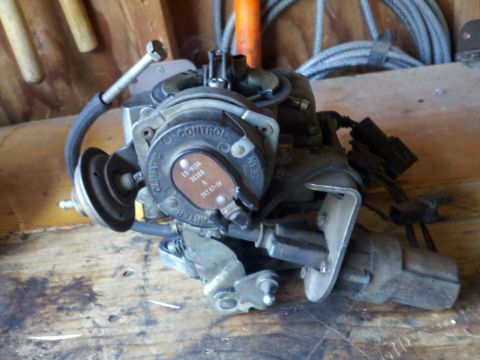1986 Ford Bronco - A Ford 2150 carburetor sits on a wooden surface, showing its part number and control markings.