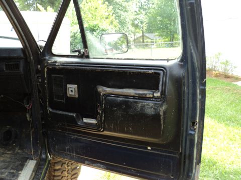 1986 Ford Bronco - Interior view of a vehicle's black door panel, showing wear and tear.
