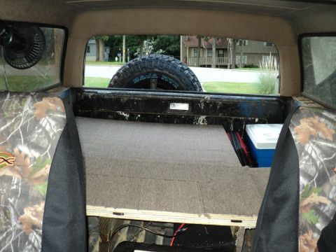 1986 Ford Bronco - The interior of a 1986 Ford Bronco features camouflage seat covers and a spare tire mounted at the rear.