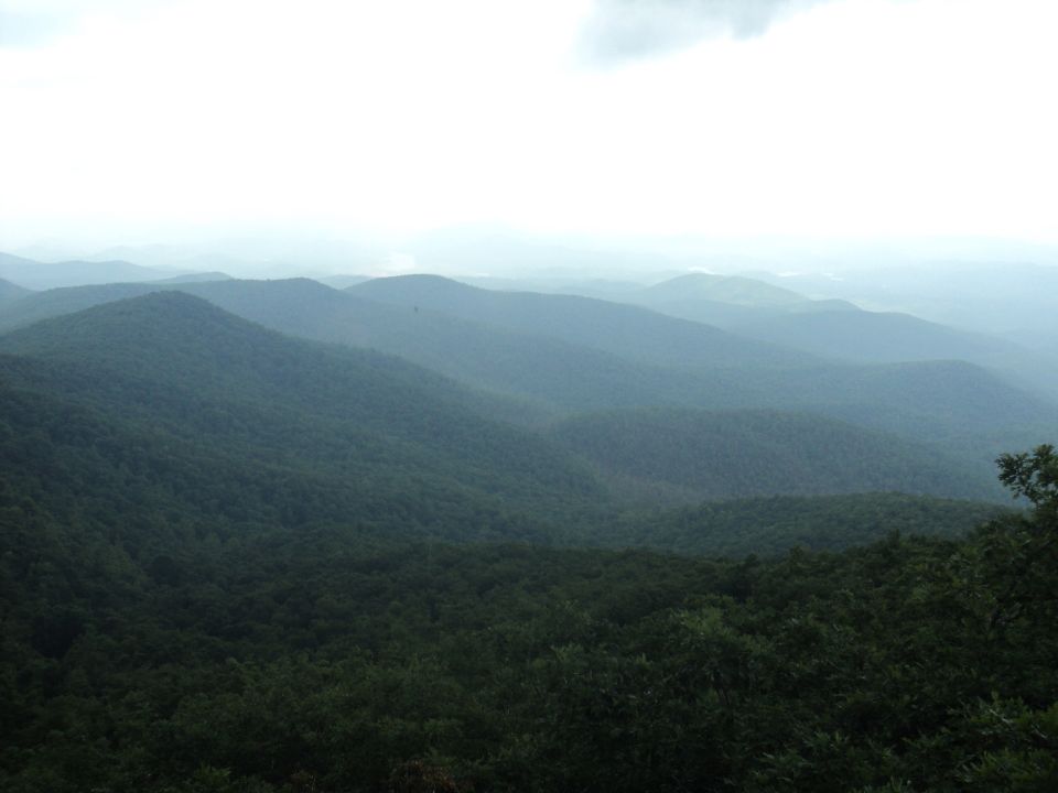 Hazy mountain range with trees covering the slopes under a cloudy sky