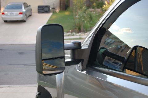 2007 Chevrolet Silverado 1500 - Side view of a 2007 Chevrolet Silverado 1500 showing its towing mirror, with another car parked in the background.