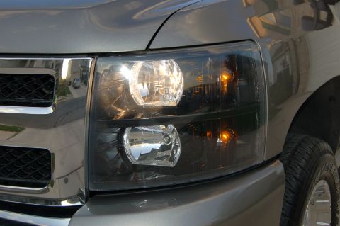 2007 Chevrolet Silverado 1500 - Front view of a gray truck's headlight and grille assembly, showing the headlights illuminated.