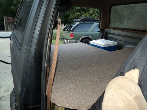 1986 Ford Bronco - Looking into the back of a vehicle, with a cooler and another SUV visible through the open door.