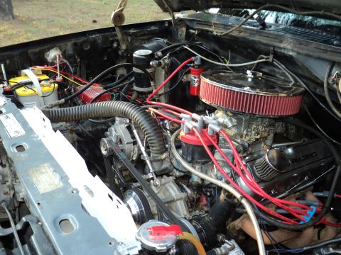 1986 Ford Bronco - Close-up view of a modified V8 engine bay with red spark plug wires and a chrome air filter.