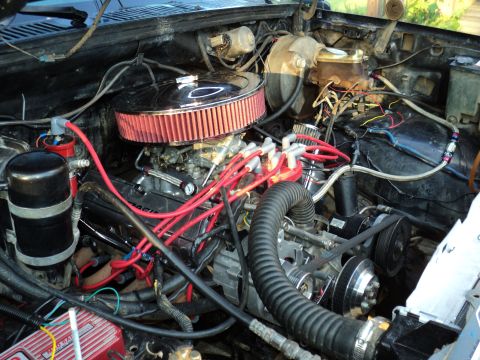 1986 Ford Bronco - The engine bay features a chrome air cleaner and bright red spark plug wires, suggesting performance modifications.