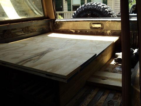 1986 Ford Bronco - Custom plywood platform installed in the cargo area of a vehicle, spare tire visible.