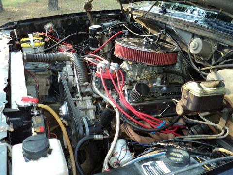 1986 Ford Bronco - The engine bay of a vehicle, showing the V8 engine, radiator, and various hoses and wires.