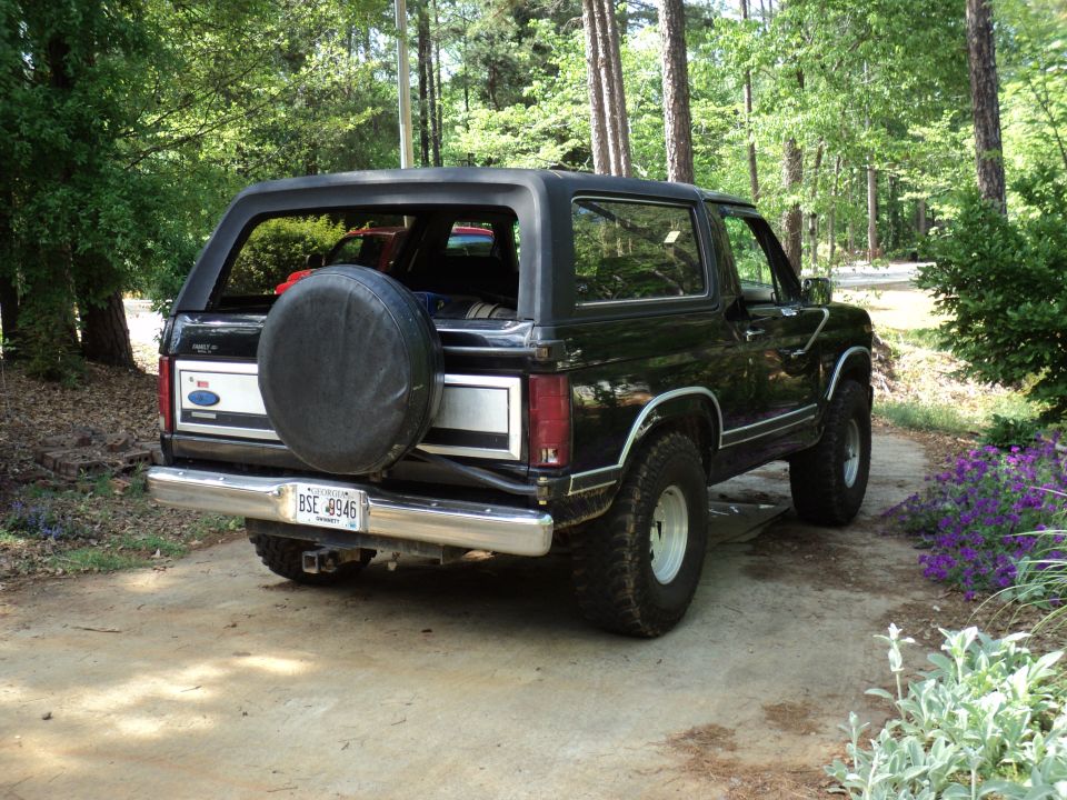 Black Ford Bronco parked on a driveway, rear view, with a spare tire cover and license plate BSE 8946