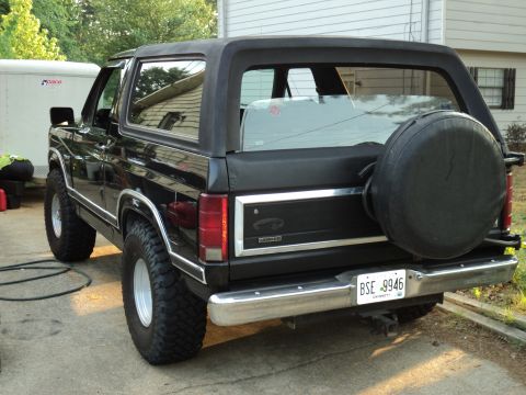 1986 Ford Bronco - Rear view of a black 1986 Ford Bronco parked outdoors, showing its spare tire and license plate.
