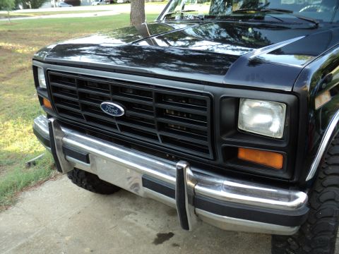1986 Ford Bronco - Front view of a black Ford Bronco, highlighting its grille and headlight assembly.