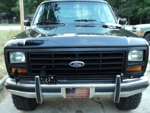 1986 Ford Bronco - Front view of a black 1986 Ford Bronco, an American flag decal on the license plate holder.