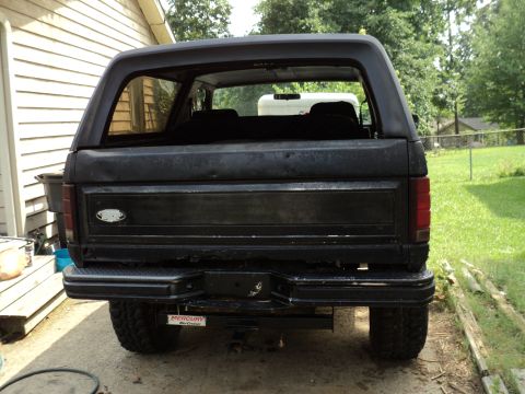 1986 Ford Bronco - Rear view of a black Ford Bronco, showing its bumper and a Mercury Marine sticker.