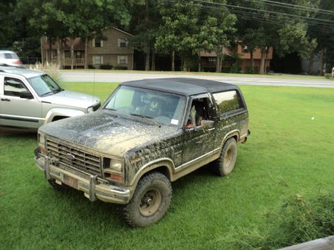 1986 Ford Bronco - This 1986 Ford Bronco is heavily covered in mud, suggesting recent off-road use.