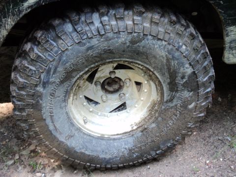 1986 Ford Bronco - A close-up view of a muddy tire and wheel on an off-road vehicle.