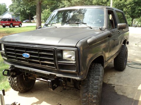 1986 Ford Bronco - This Ford Bronco has a snorkel and is parked in a driveway with another vehicle in the background.