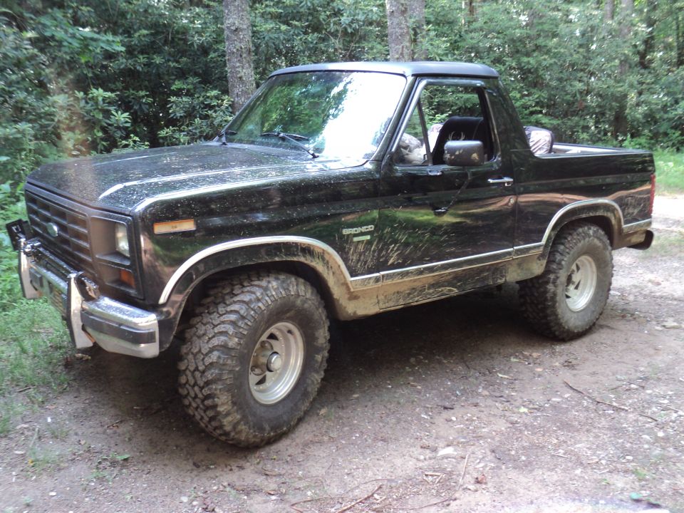 Black Ford Bronco with lifted suspension and off-road tires parked on a dirt path