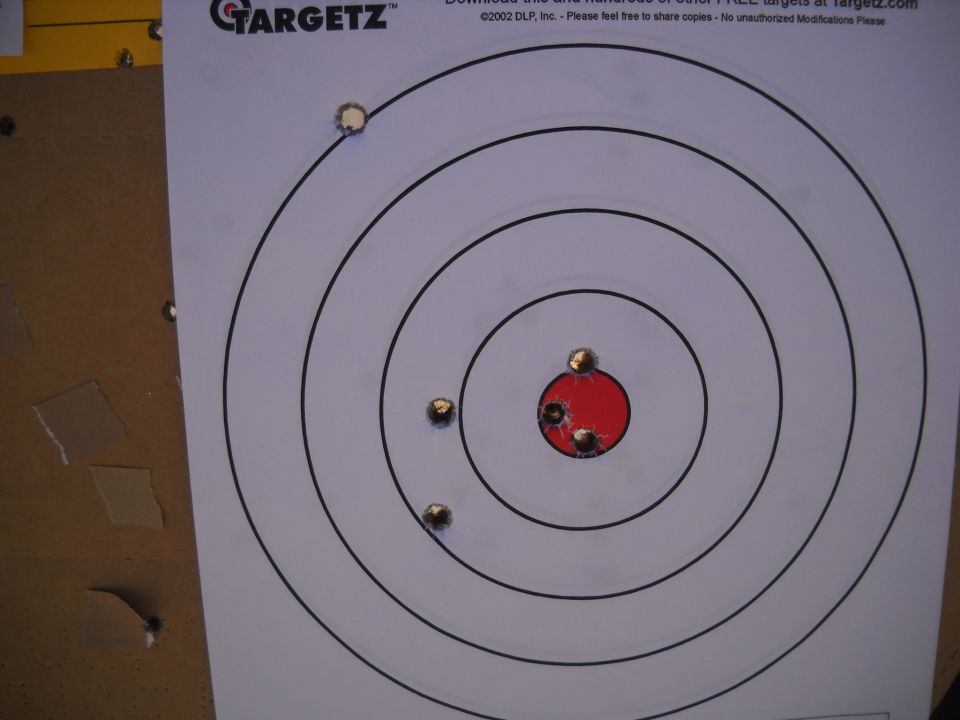 Target with bullet holes, concentric circles, and red bullseye