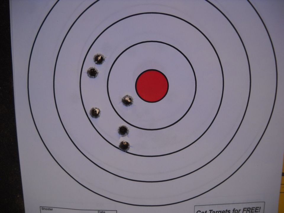 Target with bullet holes clustered around the red center