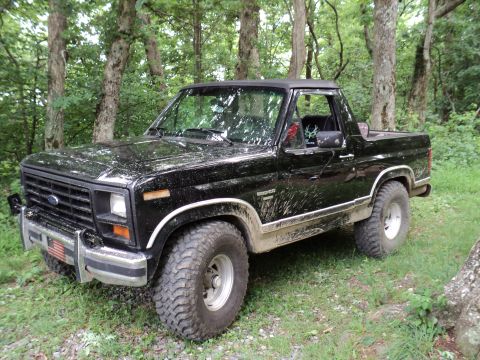1986 Ford Bronco - Black 1986 Ford Bronco with mud splatters on the body, parked outdoors.