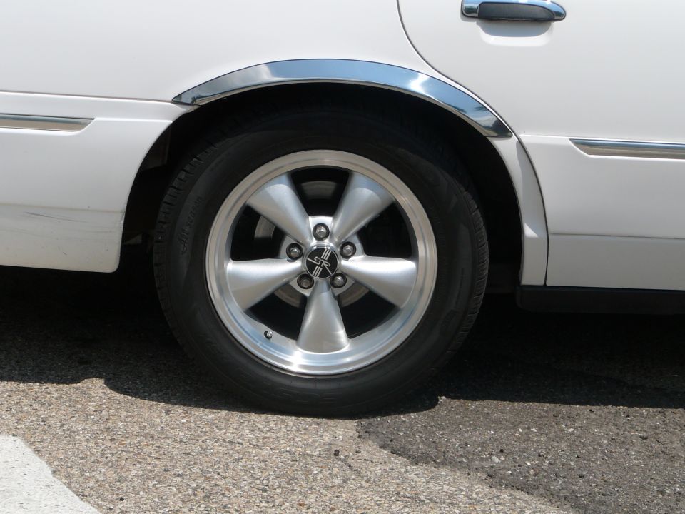 White sedan rear wheel with chrome fender trim and five-spoke alloy wheel