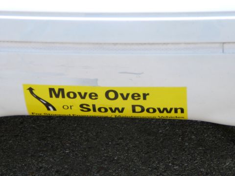 1999 Mercury Grand Marquis - Yellow sticker with traffic safety message is affixed to a white surface, possibly a vehicle bumper.