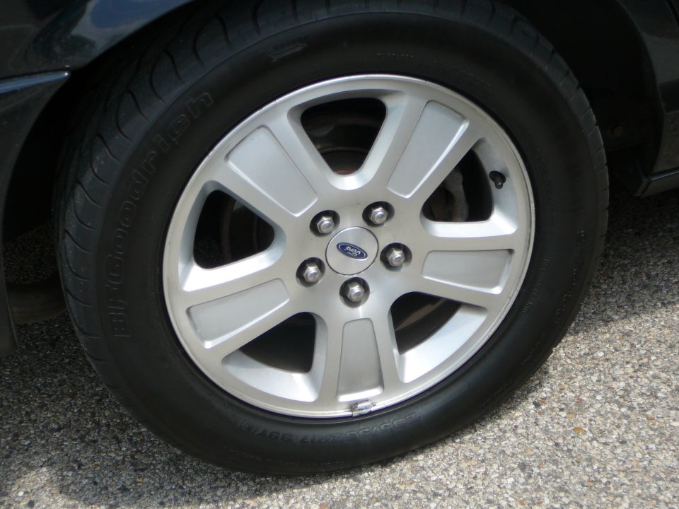 Silver alloy wheel with a Ford logo on a black tire. The wheel has five spokes
