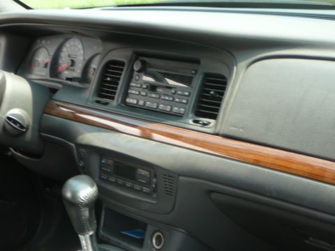 1999 Mercury Grand Marquis - The interior dashboard of a 1999 Mercury Grand Marquis features wood trim accents and a central radio unit.