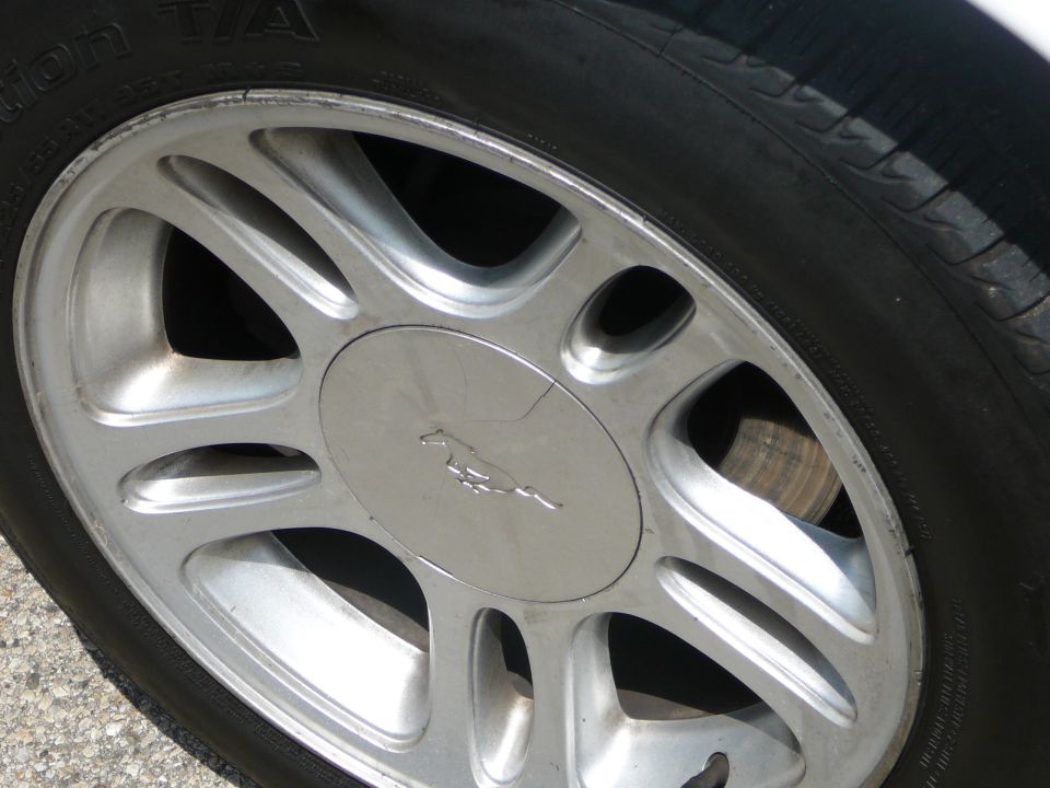 Silver alloy wheel with a running horse emblem and tire sidewall text