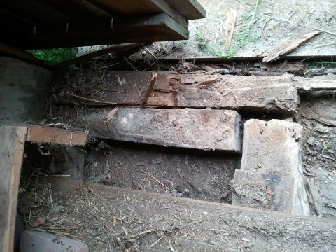 1985 Ford F-150 - A close-up view of decaying wooden beams and surrounding debris, with the Supermotors.net logo in the lower right corner.
