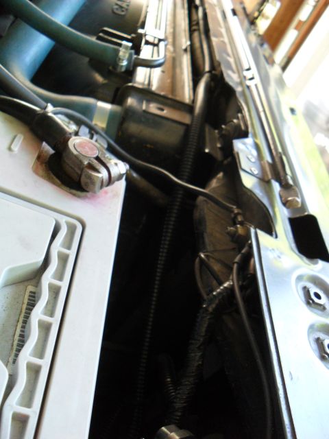 1990 Ford Bronco - Close-up view of automotive engine bay components, including battery terminals and wiring harnesses.