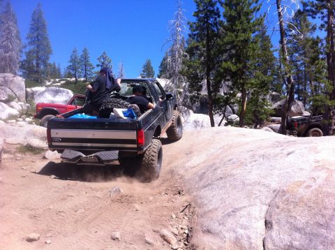 1990 Ford Bronco - 1990 Ford Bronco navigating a challenging off-road course with friends in the back.