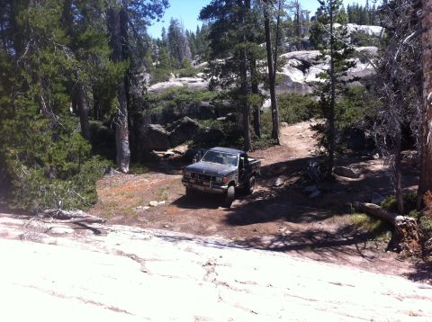 1990 Ford Bronco - A dark gray Ford Ranger pickup truck is parked on a dirt road surrounded by trees and rocks.