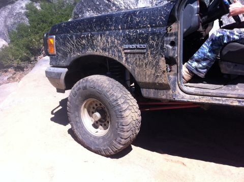 1990 Ford Bronco - Mud-covered 1990 Ford Bronco seen off-road, with the 'Bronco' badge visible on the fender.