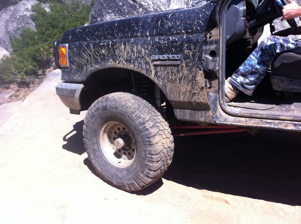 Black 1990 Ford Bronco with mud splatters, driver's side front quarter view