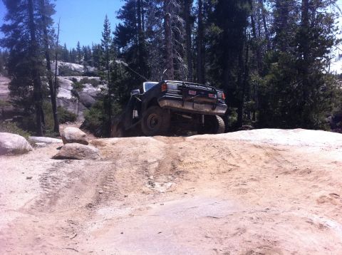 1990 Ford Bronco - This SUV is navigating a challenging off-road trail with steep inclines and rocky terrain.