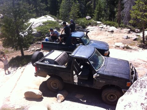 1990 Ford Bronco - Two off-road vehicles navigate a rocky trail, with a black Ford Bronco in the foreground.